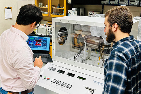 Two men stand by aerospace machinery