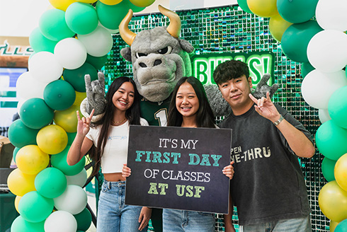 Three students stand with Rocky the Bull