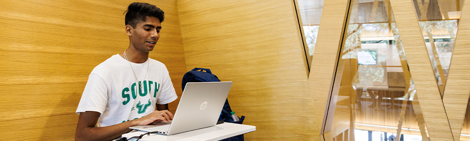 A student using his laptop in the new Judy Genshaft Honors College building.