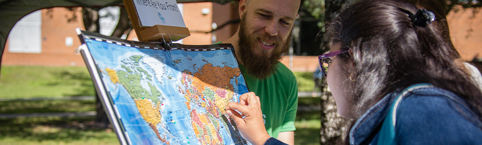 A student pointing on a world map showing where she's from.