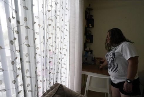 Marta Lavandier / AP A mother of four looks out the window from her apartment, Aug. 24, 2023, in Homestead. The Honduran native worked as a house painter shortly after arriving in the U.S. in 2021. Fear has forced many undocumented workers to leave the state following a new law signed by Gov. Ron DeSantis.