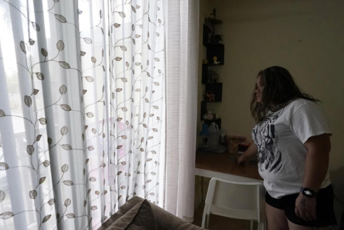 A mother of four looks out the window from her apartment, Aug. 24, 2023, in Homestead. The Honduran native worked as a house painter shortly after arriving in the U.S. in 2021. Fear has forced many undocumented workers to leave the state following a new law signed by Gov. Ron DeSantis.