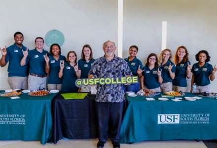 Samantha Holland Hughes (second from right) pictured with her DSLS cohort and former CAS Dean Eric Eisenberg (center), working promotional tables for the college. (Photo courtesy of Samantha Holland Hughes)