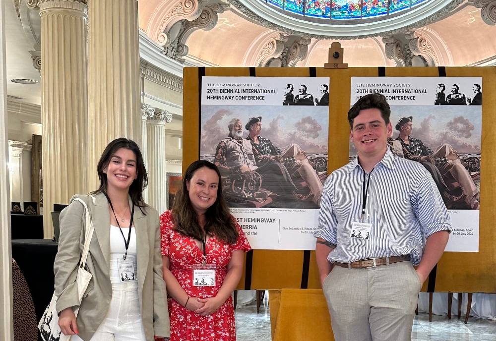 Three doctoral students presenting in front of their research posters.