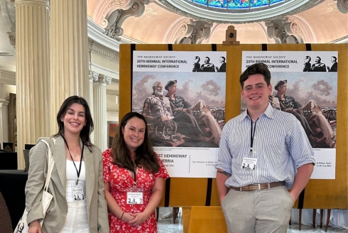 Three doctoral students presenting in front of their research posters.