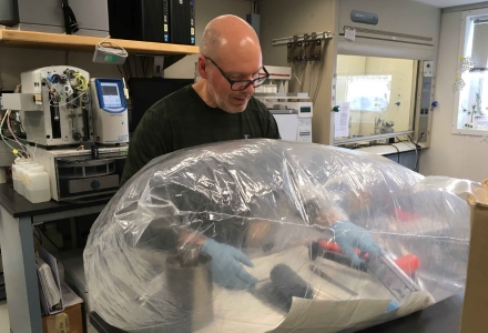Dr. Jeffrey Ryan aboard the JOIDES Resolution extracting core samples for pore fluid analysis while working in a glove bag nitrogen atmosphere. (Photo courtesy of Dr. Jeffrey Ryan)