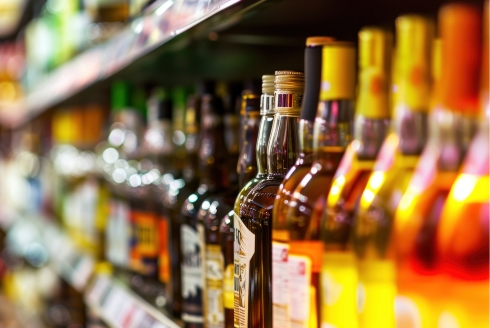 Rows of alcohol bottles on a shelf in a supermarket. (Photo source: Adobe Stock)