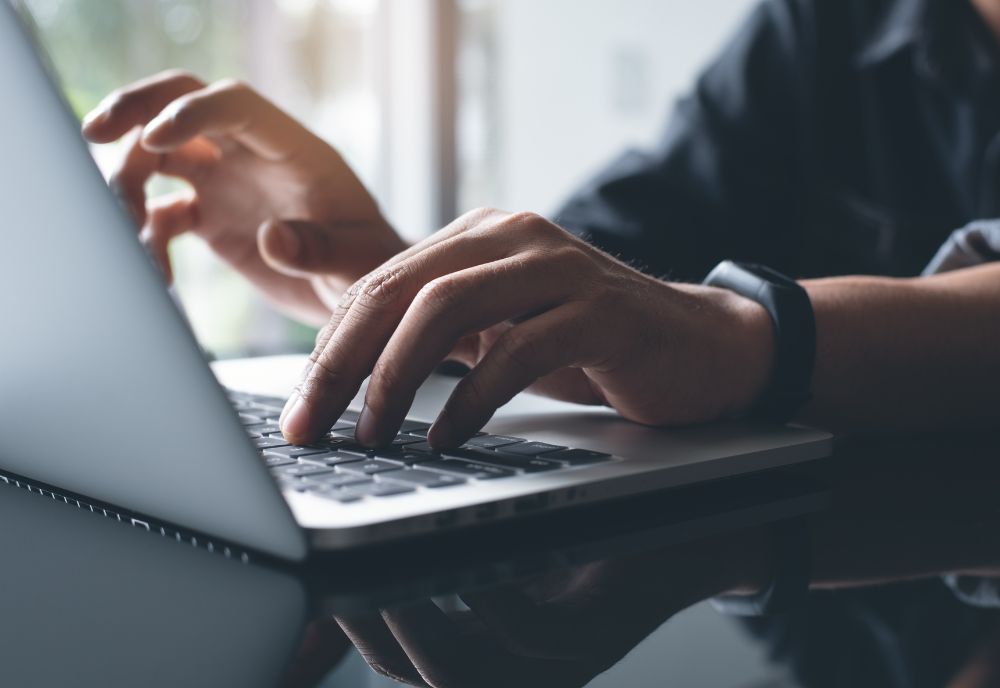 person's hands typing on laptop