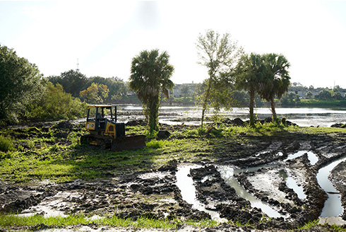 muddy tracks through land with bulldozer in background