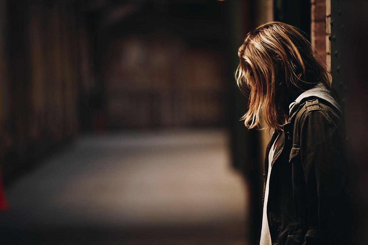 girl in dark alley gazing downward