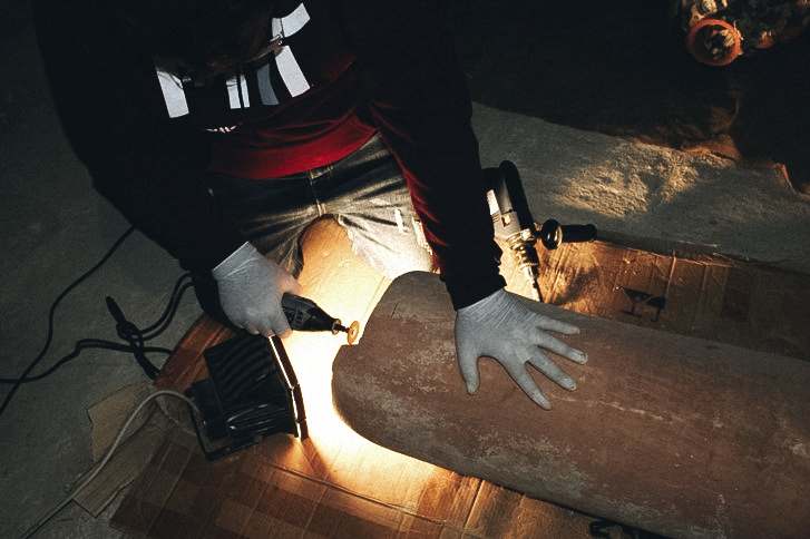 Person in mask using tool on pottery