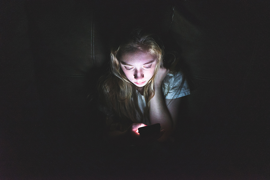 girl looking at cell phone in the dark