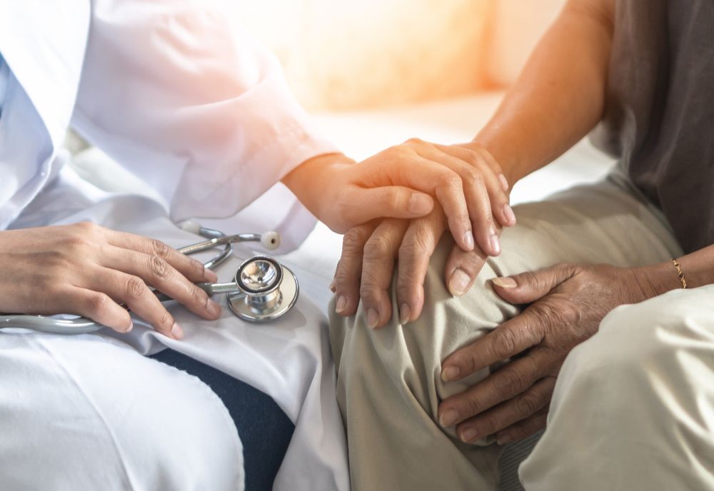 doctor's hand resting on patient's hand to comfort
