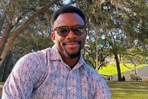 Olajide Omojarabi smiling at the camera with sunglasses on