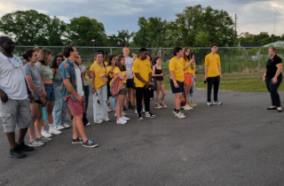 group of students in yellow shirts listening to teach lecture outside