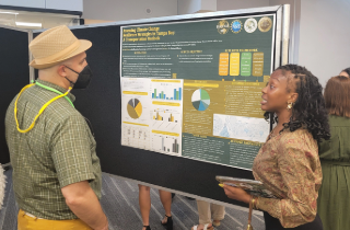 photo of woman speaking with man in front of presentation poster