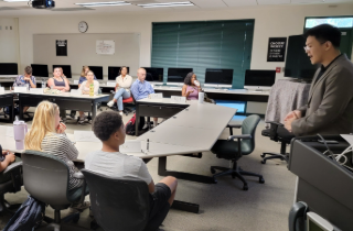 group of students sitting in computer lab while professor lectures