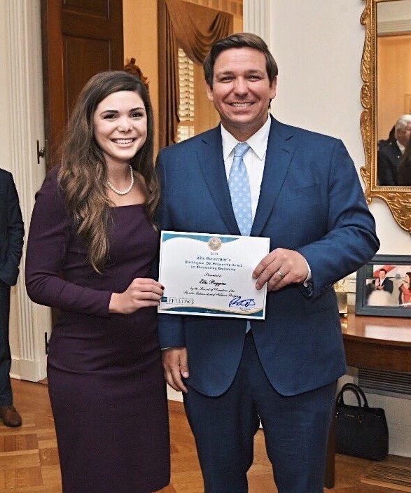 Ella Biggins accepting her award from Florida Governor Ron DeSantis.