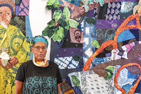 Lauren Austin stands in front of her quilt exhibit