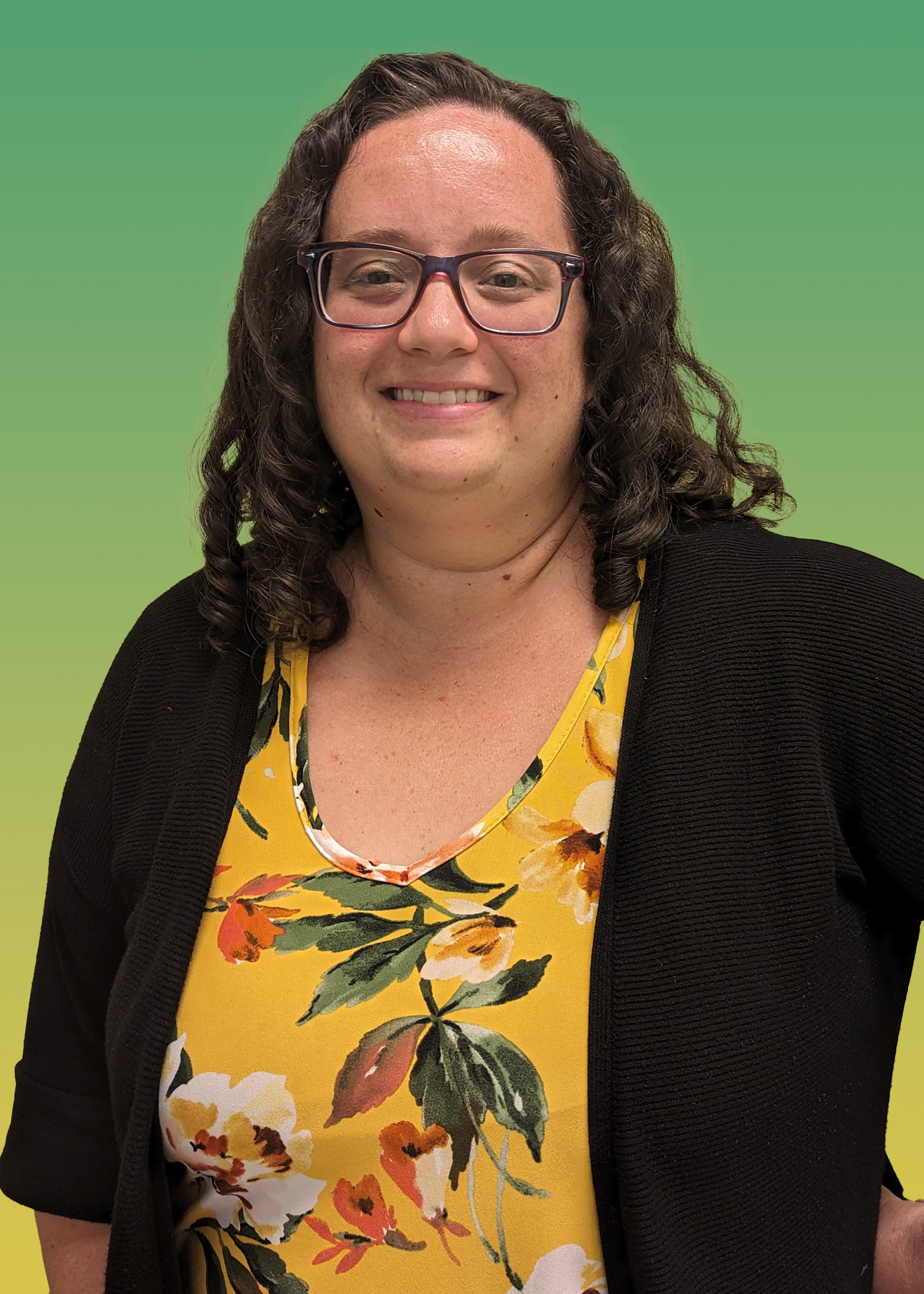 Portrait of Jessica Hoffmann wearing a blue floral shirt, a black cardigan, and glasses.