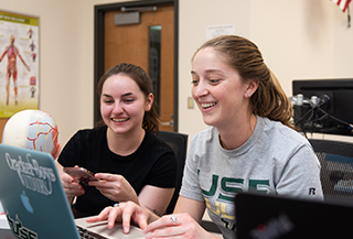 students laughing while working on laptop