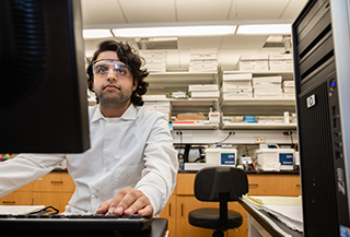 student working on laptop wearing protective goggles