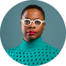 Headshot of Nathalie wearing a turtleneck sweater and white framed glasses