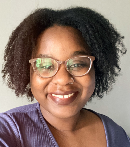 Headshot of Alanah Cooper, LHI Research Assistant. She is wearing her natural curls, brown glasses, and a periwinkle top. 