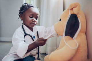 Little girl playing doctor with stuff toy.