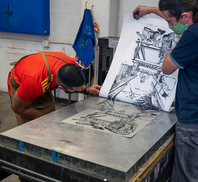 Serhat Tanyolacar lifts a print from the press for a student to examine.