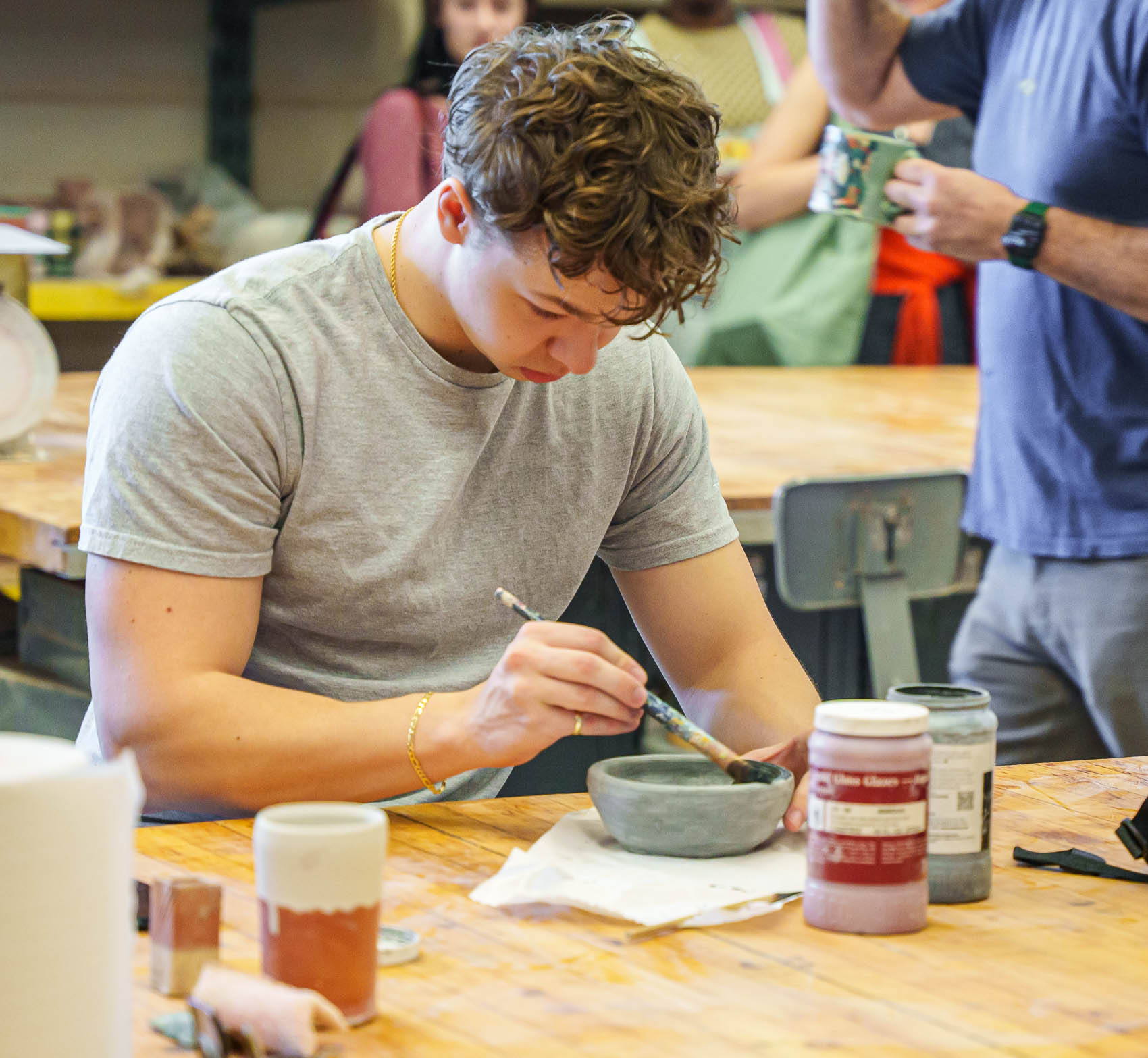 Student painting glaze on a piece of ceramics.