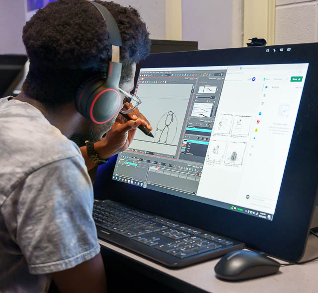 A student draws on a screen with a stylus.