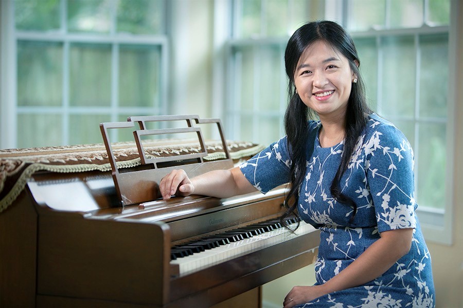 Sungkyeong Kim wearing a blue dress sitting at a piano