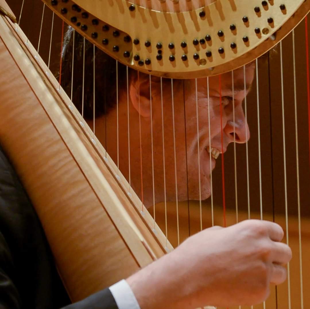 Headshot image of John McColley playing the harp