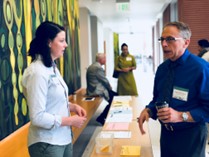 Two people standing on either side of a conference check-in table while having a conversation.