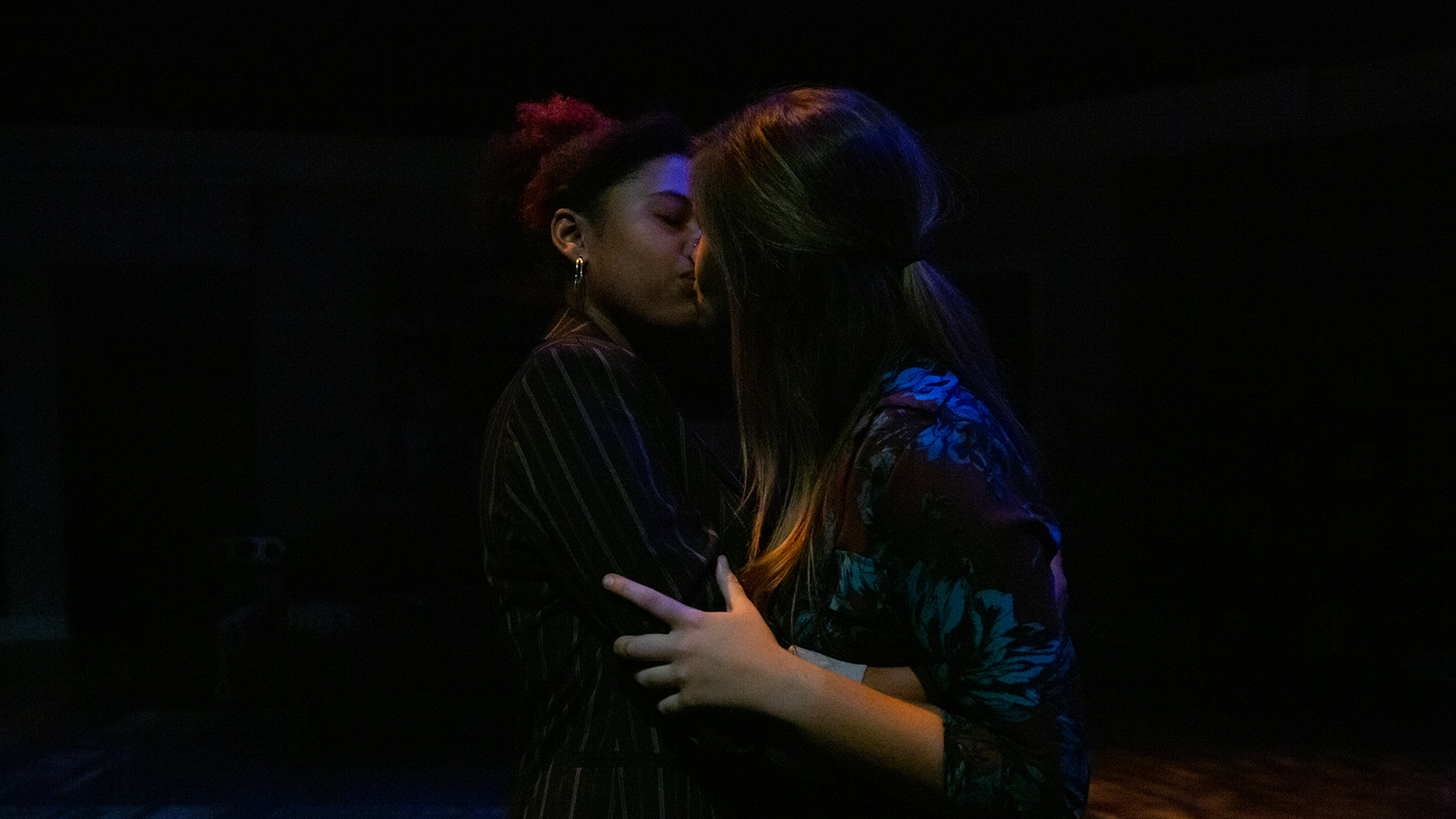 The two main women characters of Stop Kiss embrace each other as they kiss.