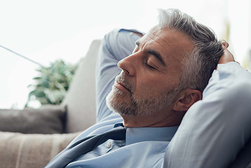 Man in a dress shirt and tie with hands behind his head sleeping