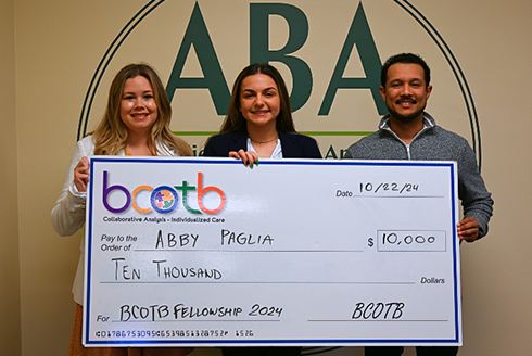 Abby Paglia receives a check alongside Anthony Concepción and Heatherann Tenowich