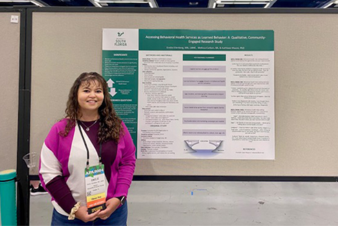 Emilie Ellenberg stands in front of her research poster