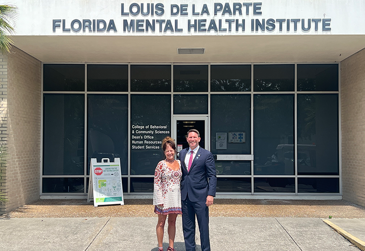 Kathleen Moore and David Silvers stand outside the College of Behavioral and Community Sciences building