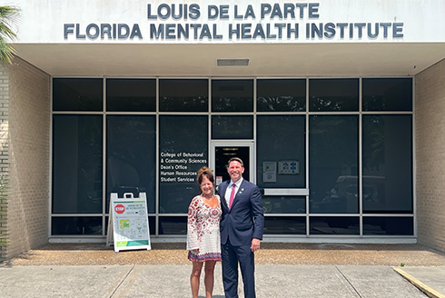 Kathleen Moore and David Silvers stand outside the College of Behavioral and Community Sciences building