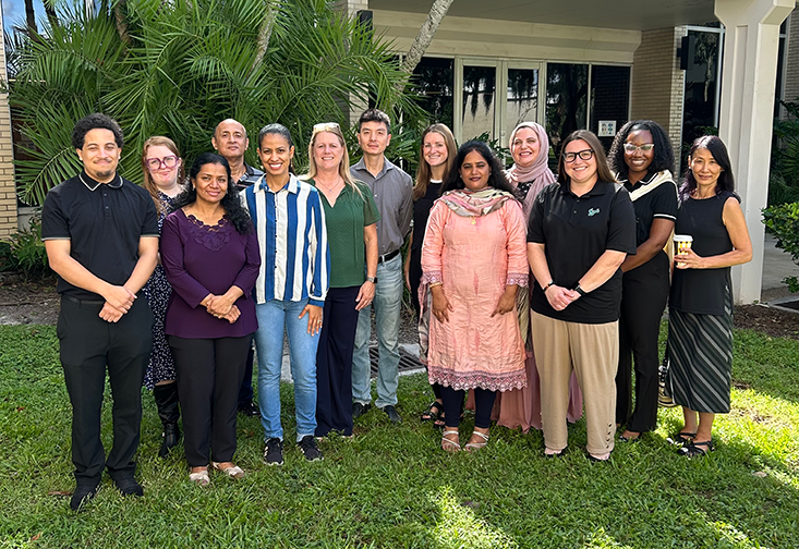 A large group poses for a photo outside of the School of Aging Studies building.