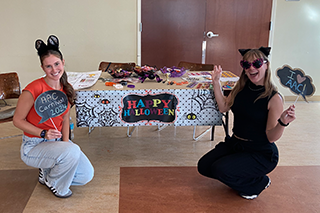 Natalie Kozak and Lexis Kreimeier in front of Happy Halloween sign