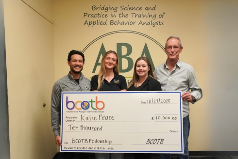 Anthony Concepcion, Katie Pease, Heatherann Tenowich, and Ray Miltenberger holding the ten thousand dollar check in front of the ABA wall art