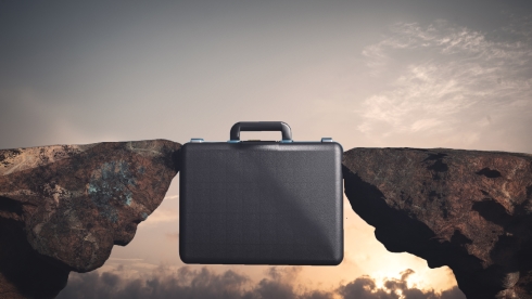 A briefcase bridging two rock cliffs