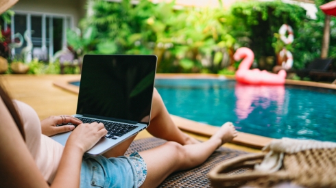 A woman working at a laptop while poolside