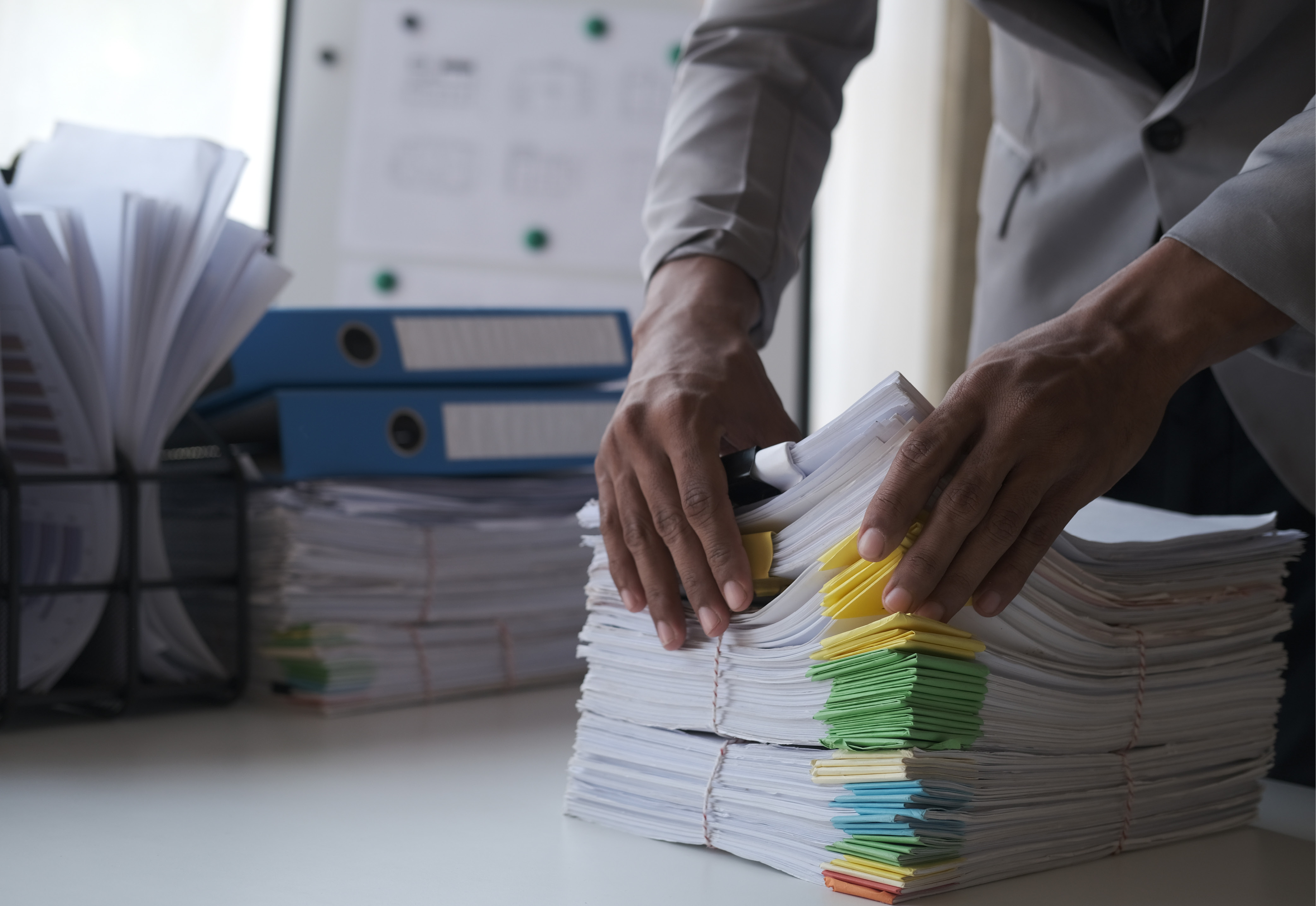 A person holding a stack of papers on a desk