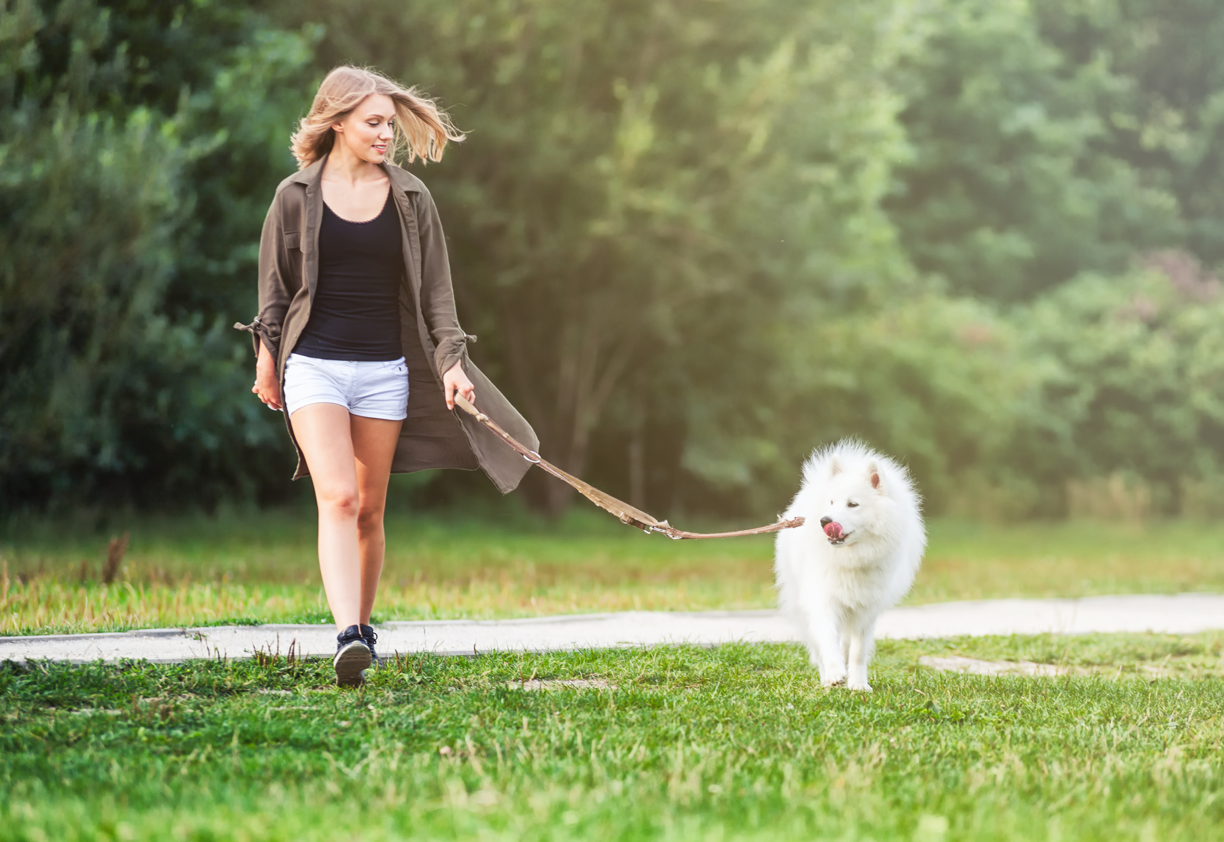 A woman walking her dog through grass
