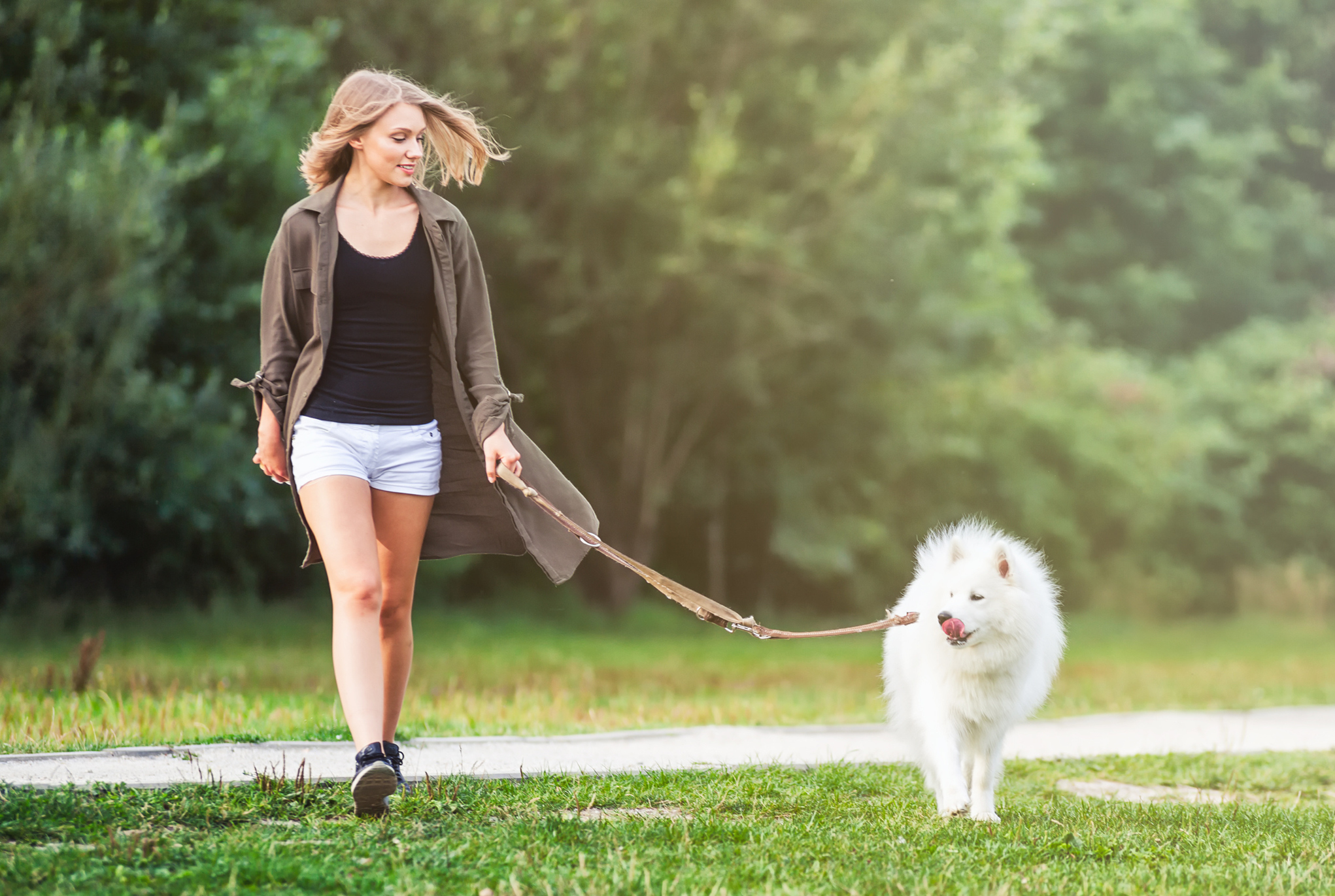 A woman walking her dog through grass