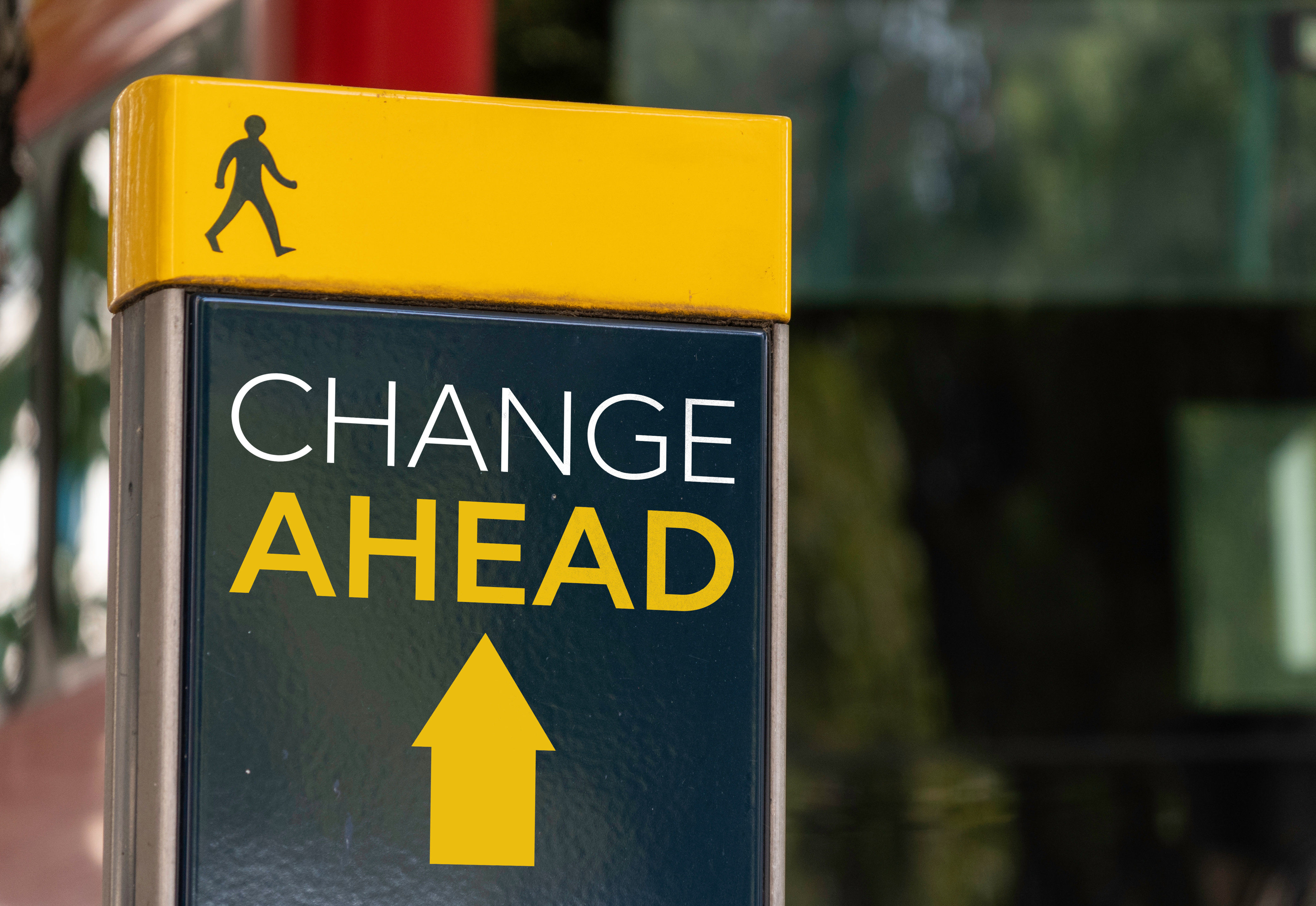 A black and yellow sign labeled, "Change Ahead" with an icon of a person walking and an arrow pointing forward